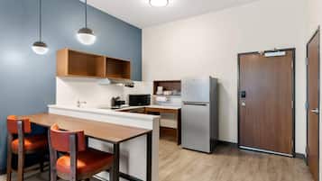 Una cocina compacta con comedor, microondas, refrigerador y una puerta de madera.