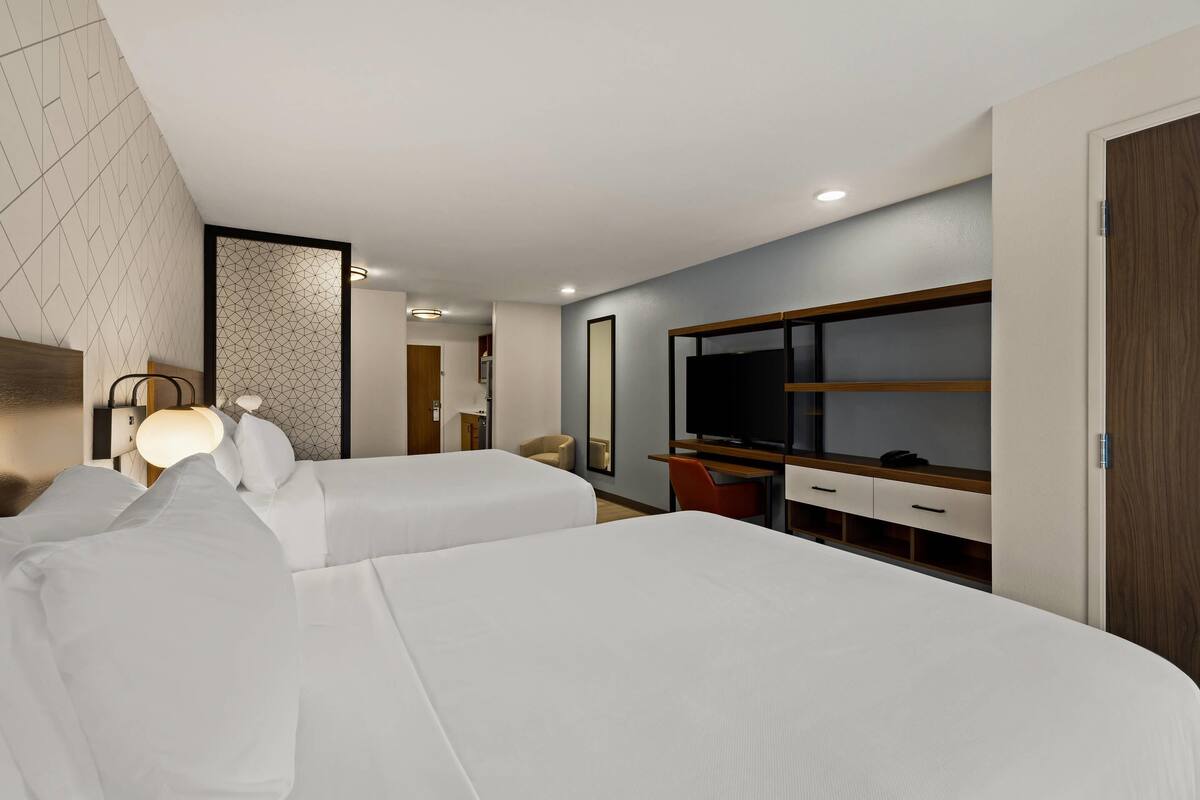 Une chambre d’hôtel avec deux lits, une télévision, un bureau et une armoire.