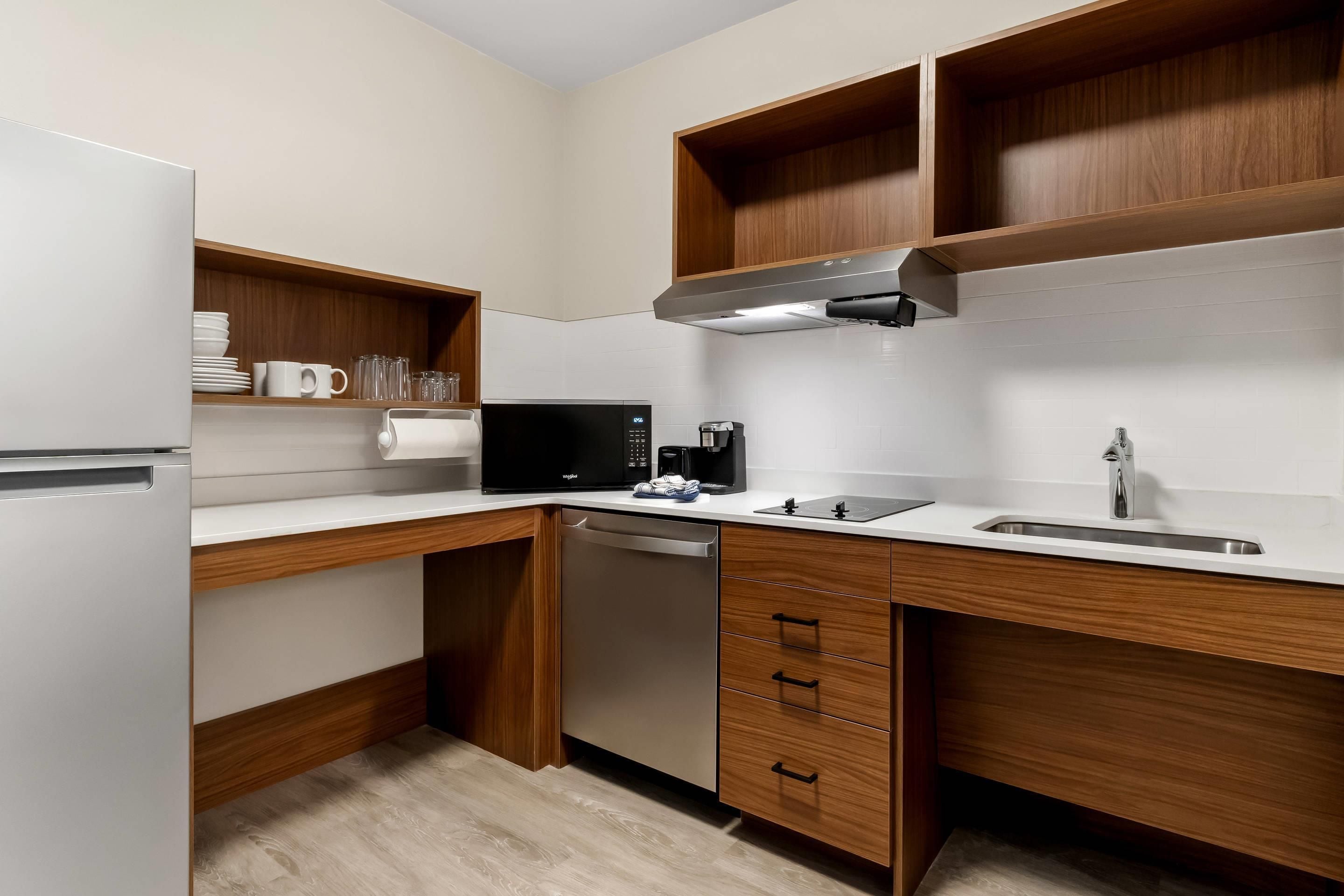 A compact kitchen with a refrigerator, microwave, coffee maker, and a dishwasher.