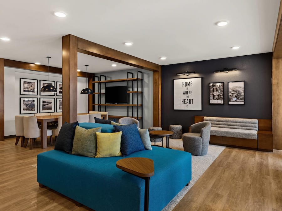 Een moderne woonkamer met een blauwe bank, houten details en een eethoek met stoelen en een tafel.