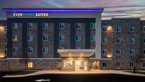 Un hotel moderno con fachada de piedra, una entrada destacada y un letrero que dice 'Everhome Suites'.
