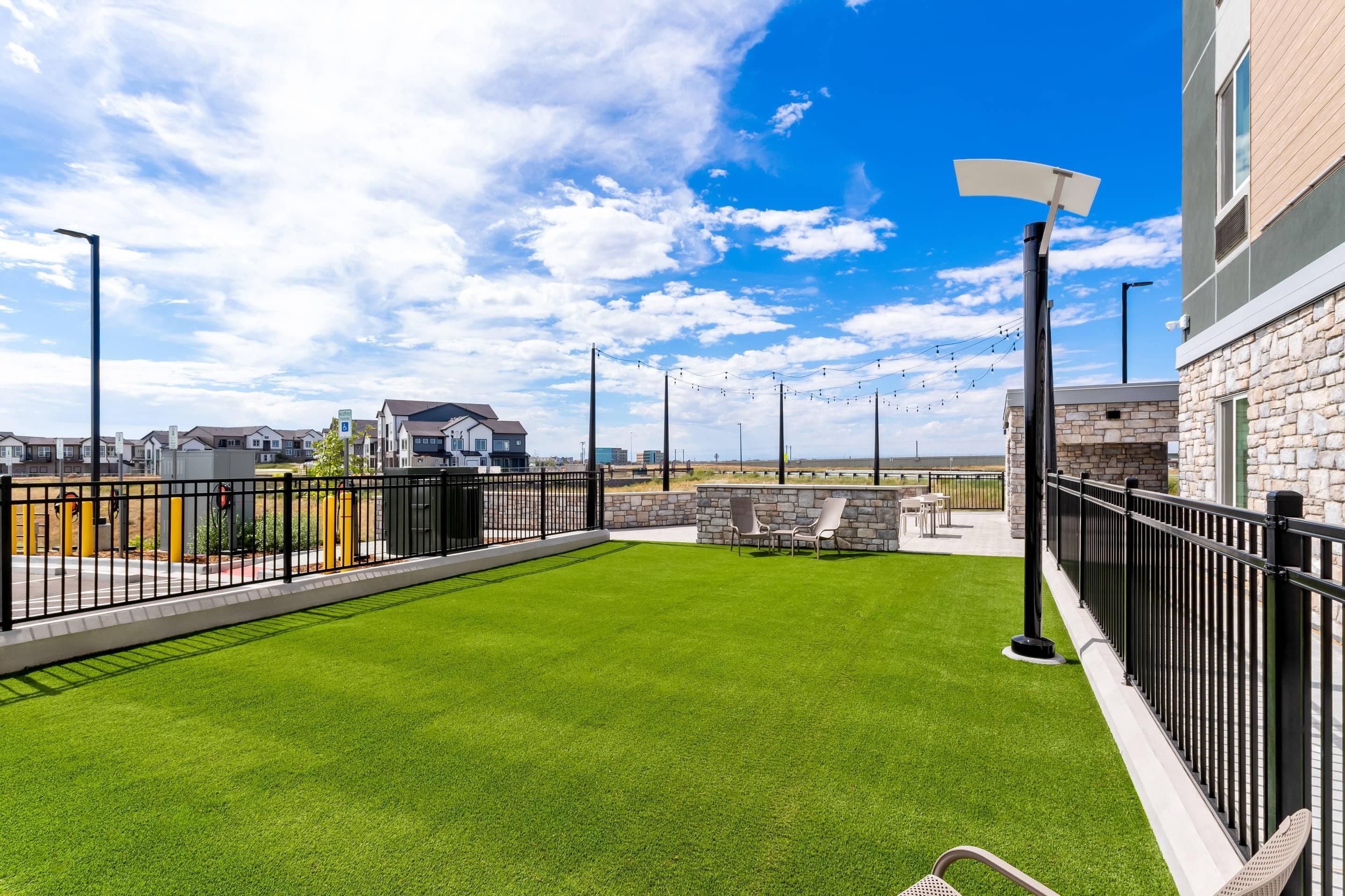 Une terrasse sur le toit, dotée d’un revêtement d’herbe artificielle, de sièges d’extérieur et offrant une vue dégagée sur les environs.