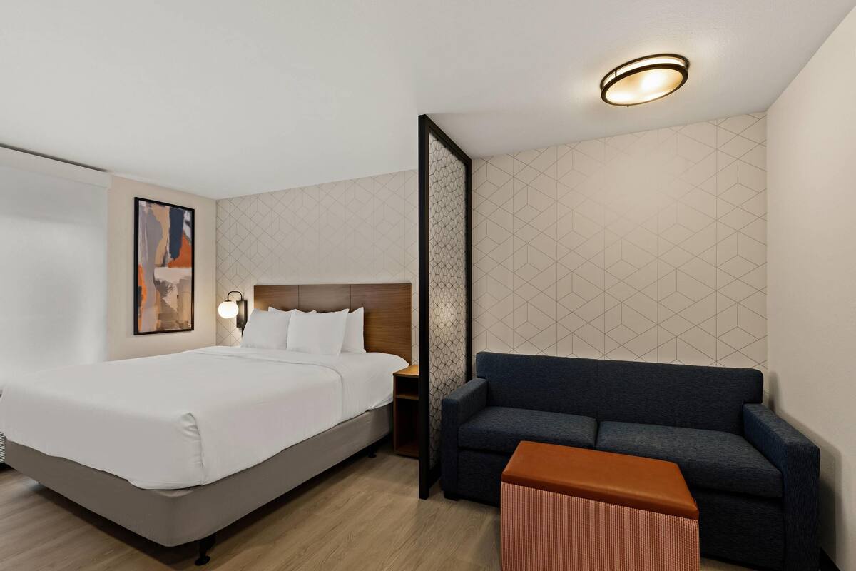Une chambre d’hôtel avec un lit, un canapé, une petite table et une table de chevet.