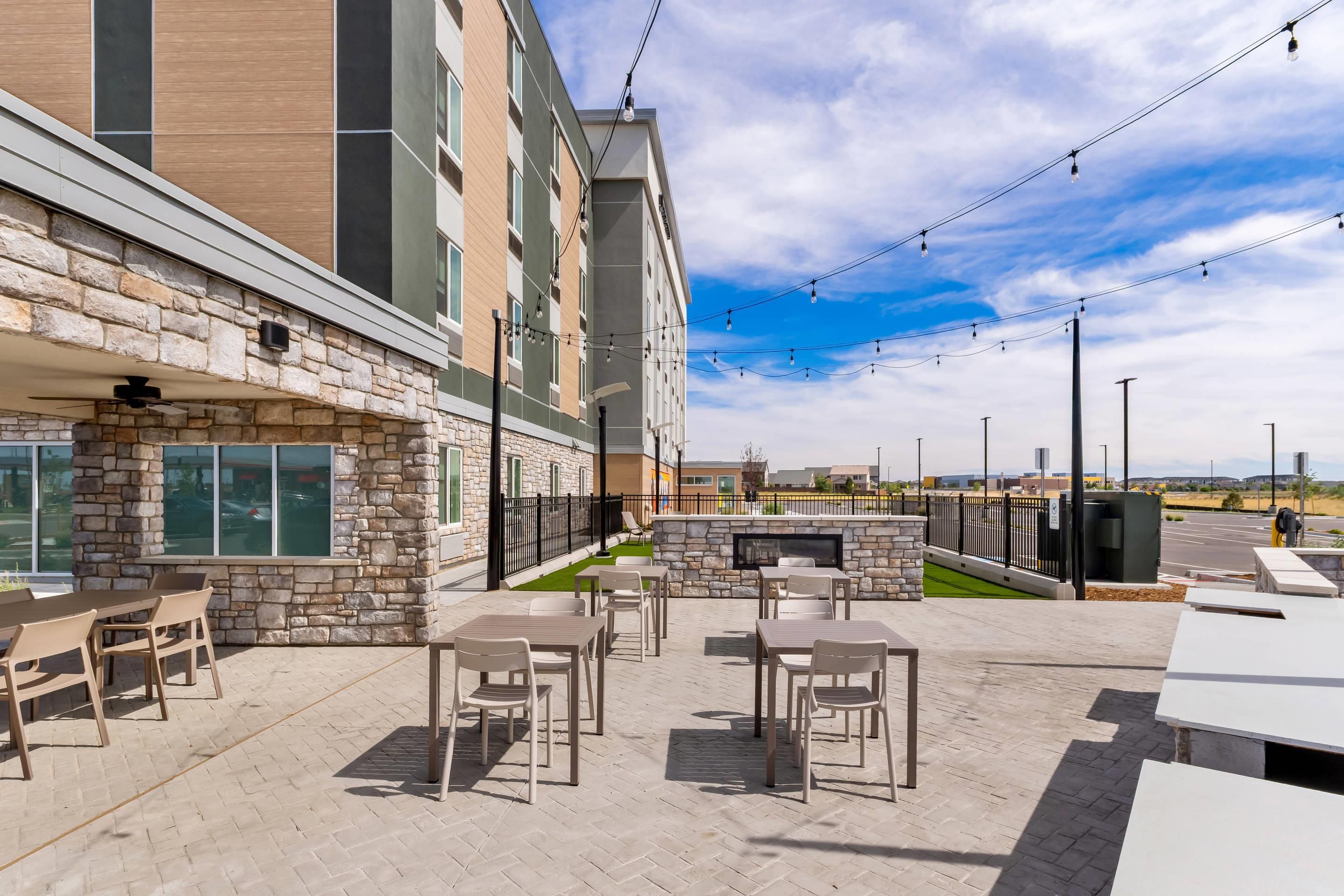 Un patio con mesas al aire libre, una pared de piedra y vistas a un estacionamiento.
