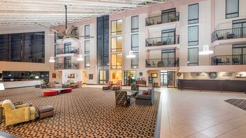 A spacious lobby with a high ceiling, multiple balconies, and a variety of seating arrangements.