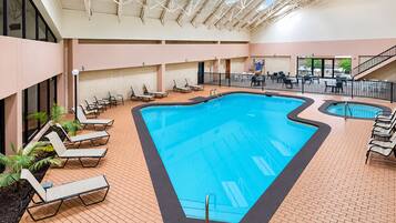 An indoor swimming pool with lounge chairs and a staircase.