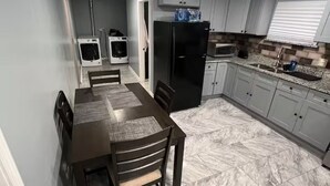 Une cuisine compacte comprenant une table à manger, des chaises, un réfrigérateur, un four à micro-ondes et un four encastré.