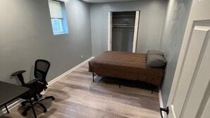Une chambre à coucher avec un lit, une chaise, une table et une fenêtre.