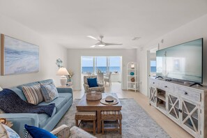 A living room with a sofa, coffee table, TV, and a view of the ocean. - Gulf-to-Bay Luxury: Million Dollar Views at this Newly Remodeled Beachfront Ground Floor Condo (Sarasota)