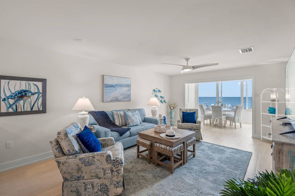 A living room with a sofa, a coffee table, and a dining area with chairs.