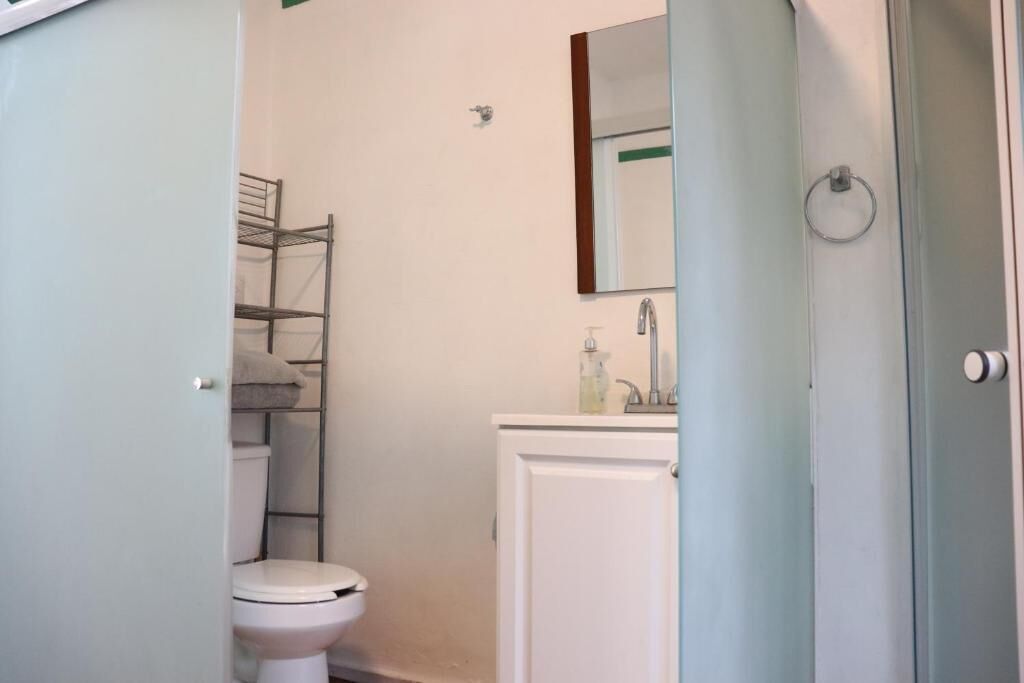 Un baño con inodoro, repisa, espejo y lavamanos.