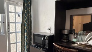 A compact kitchen with a microwave, coffee maker, and a small dining area with a chair. - The 222 (Mexico City)