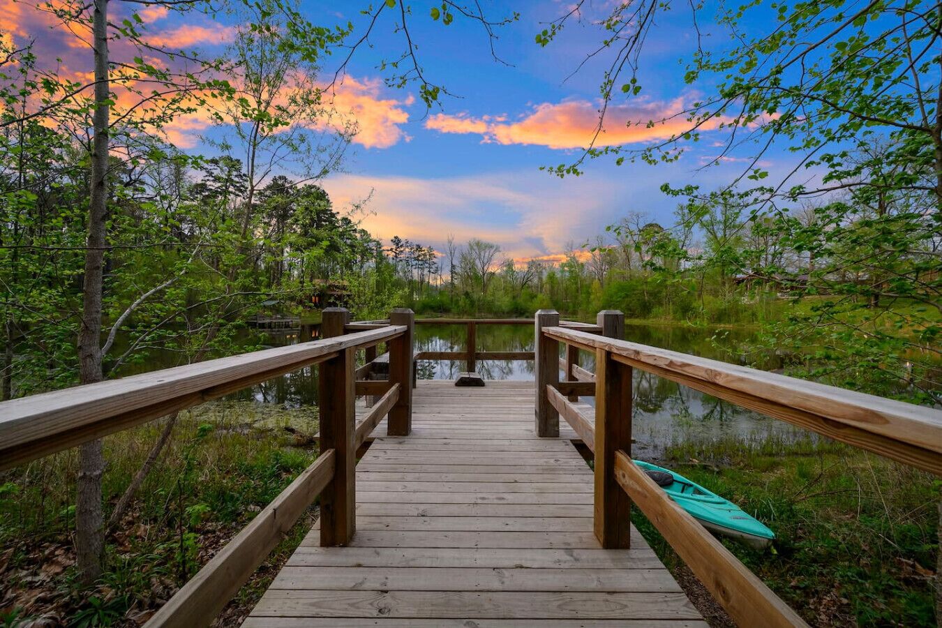 A wooden boardwalk leading to a body of water, surrounded by trees and vegetation.