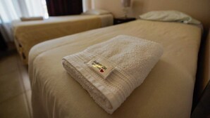 A hotel room with two beds, each with a neatly folded white towel and a tag. - Complejo Anjana (Federación)