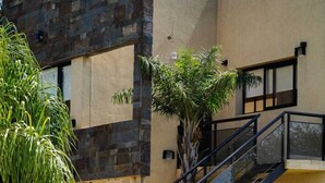 A modern building with a stone facade, a staircase, and surrounding greenery. - Complejo Anjana (Federación)