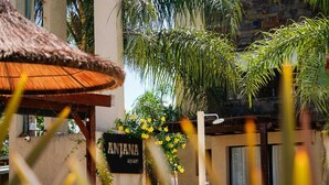 A building with a sign reading 'ANJANA apar' surrounded by greenery and a thatched structure. - Complejo Anjana (Federación)