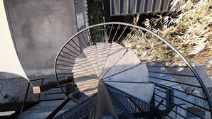 A spiral staircase with metal railings and stone steps, leading to an upper level. - Rooftop Movie House w/ Stunning views ❤️ East Austin Studio | Free Parking (Austin)