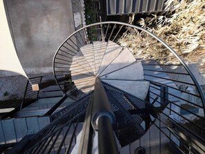 Eine Wendeltreppe mit Metallgeländern und Steinstufen, die zu einer erhöhten Ebene führt.