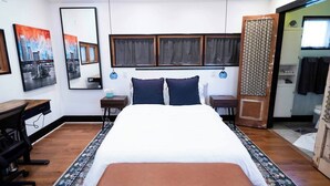 A bedroom with a bed, bedside tables, a desk, a chair, and artwork on the walls. - Rooftop Movie House w/ Stunning views ❤️ East Austin Studio | Free Parking (Austin)
