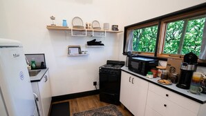 A compact kitchen with a refrigerator, stove, microwave, and a window with a view of trees. - Rooftop Movie House w/ Stunning views ❤️ East Austin Studio | Free Parking (Austin)