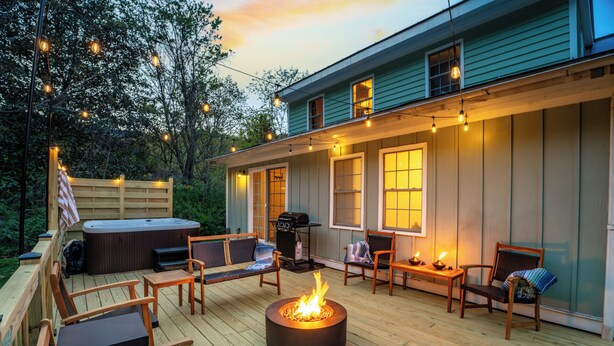 Eine Terrasse mit Gartenmöbeln, einem Feuerkorb und Lichterketten.
