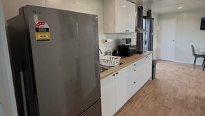 Eine moderne Küche mit weißen Schränken, einem Edelstahlkühlschrank und einer Holz Arbeitsplatte.