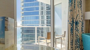 Habitación de hotel con balcón, vista a un edificio alto y cortina estampada.