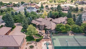 A residential area with a tennis court, a stone patio, and a large house with a stone facade. - Cottage #1: Italian Resort-Style Villa - 1.4 Acres w/ Pickleball,  In-ground Spa (Parowan)