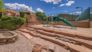 A playground with a slide, steps, and a fenced area. - Cottage #1: Italian Resort-Style Villa - 1.4 Acres w/ Pickleball,  In-ground Spa (Parowan)