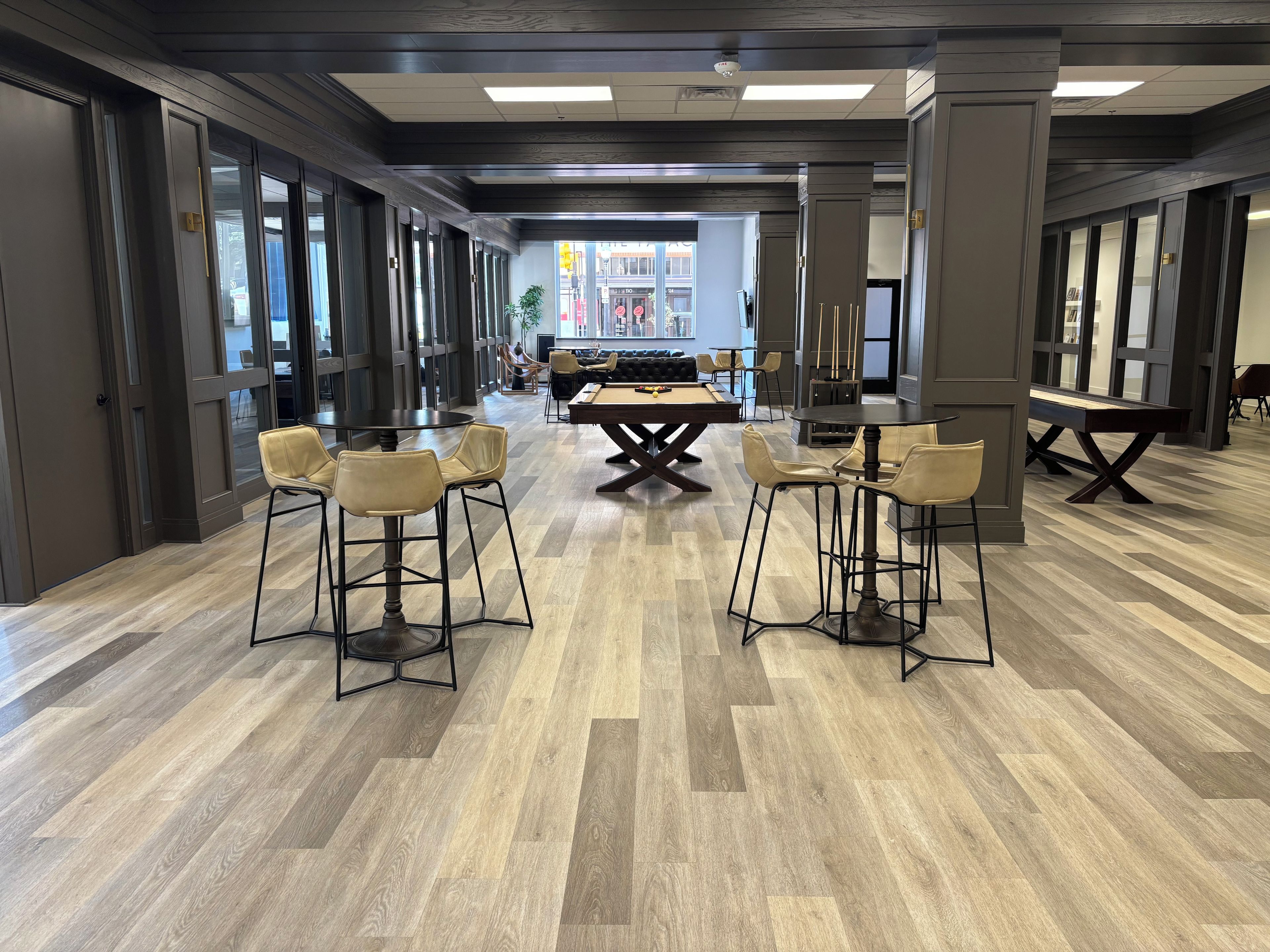 Una habitación amplia con mesa de billar, taburetes de bar y comedor con una mesa grande.
