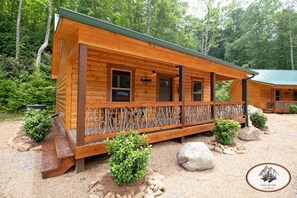 Eine Holzhütte mit Veranda, umgeben von Bäumen und Kies.