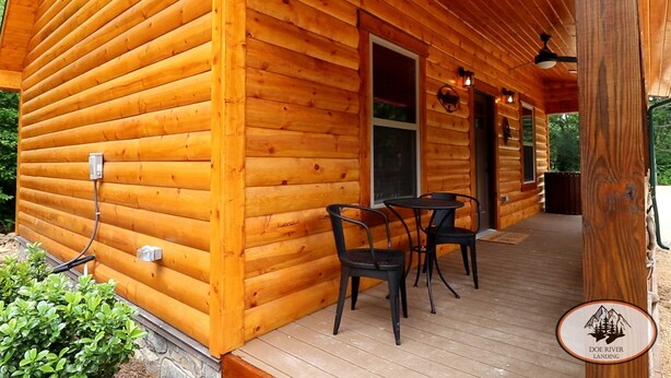 Een houten chalet met een veranda, een tafel en stoelen.