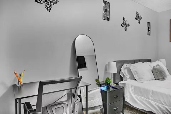 Une chambre à coucher comprenant un lit, une table de chevet, une lampe et un bureau avec une chaise.