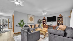 Una sala de estar moderna con un sofá gris, una mesa de centro, un televisor y una estantería.
