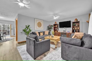 A modern living room with a grey sofa set, a coffee table, a TV, and a bookshelf. - Cozy stylish home near Akron ~Canton/ sleeps 8 (Akron)