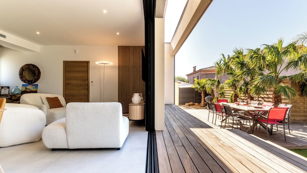 Een moderne woonkamer met een bank, een eethoek met tafel en stoelen, en uitzicht op buiten.