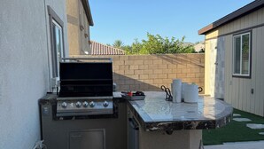Cocina exterior con una parrilla, un lavamanos y dos tanques de propano.