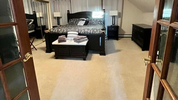 A bedroom with a bed, bedside tables, a ceiling fan, and a window with curtains. - Cozy 4-bedroom cottage in superb Conneaut with AC (Conneaut)