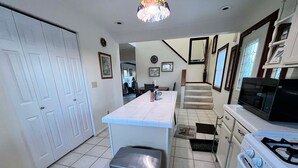 A kitchen with white cabinets, a stove, a microwave, and a tiled floor. - Cozy 4-bedroom cottage in superb Conneaut with AC (Conneaut)