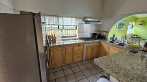 A kitchen with a stove, sink, and wooden cabinets. - Villa Cocoyoc for 23 Pax | Pool, Jacuzzi and Basketball Court (Fraccionamiento Lomas de Cocoyoc)