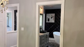 Un dormitorio con cama, cómoda, espejo y puerta que da a un baño.