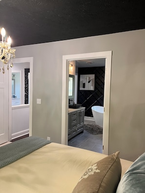 Un dormitorio con cama, cómoda, espejo y puerta que da a un baño.