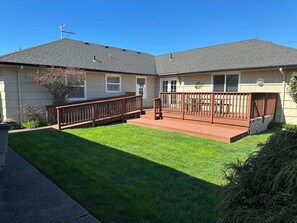 A residential house with a covered patio, a lawn, and a small garden area. - Beautiful 4-BDRM home in Seaside, steps to the beach, perfect family getaway. (Seaside)