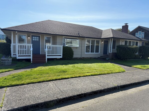 A single-story house with a front porch, a garage, and a well-maintained lawn. - Beautiful 4-BDRM home in Seaside, steps to the beach, perfect family getaway. (Seaside)