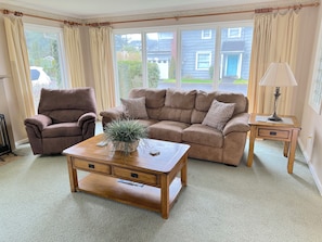 A living room with a brown leather sofa, a matching armchair, a wooden coffee table with a plant, and a side table with a lamp. - Beautiful 4-BDRM home in Seaside, steps to the beach, perfect family getaway. (Seaside)