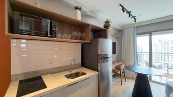 A modern kitchen with a built-in microwave, a stainless steel refrigerator, a sink, and a dining area with a table and chairs.