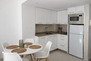Eine moderne Küche mit weißen Schränken, einer eingebauten Mikrowelle und einem Kühlschrank.