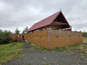 A wooden cabin with a sloped roof, a covered porch, and a gravel driveway.
