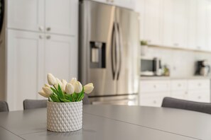 Eine weiße Vase mit Tulpen auf einem Küchentisch.