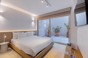 Une chambre à coucher moderne avec un lit, une table de chevet et une vue sur un balcon agrémenté de plantes en pot.